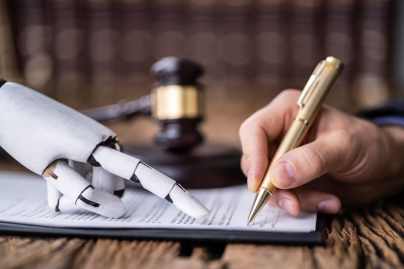 Robotic hand points to a line on a document while a human signs it with a pen. A judge's gavel is in the background.