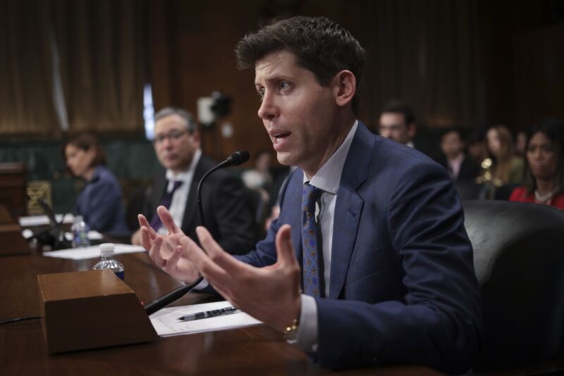 OpenAI CEO Sam Altman sits at a table and speaks into a microphone while testifying in a Senate hearing.