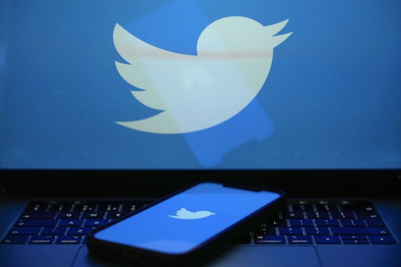 Twitter logo is seen on a laptop screen and a smartphone screen.