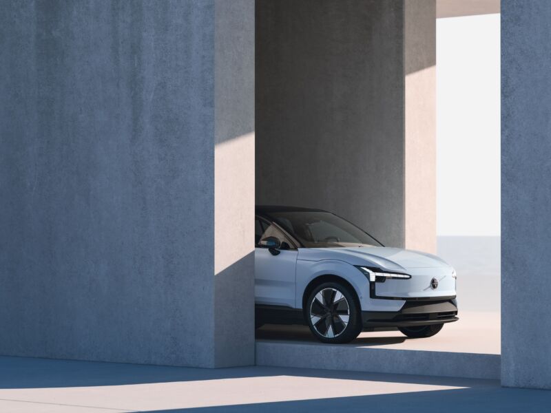 The front half of a Volvo EX30 peeking out behind a wall