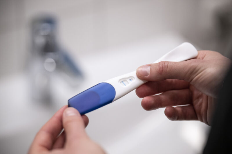 A woman holds a positive pregnancy test in her hands.