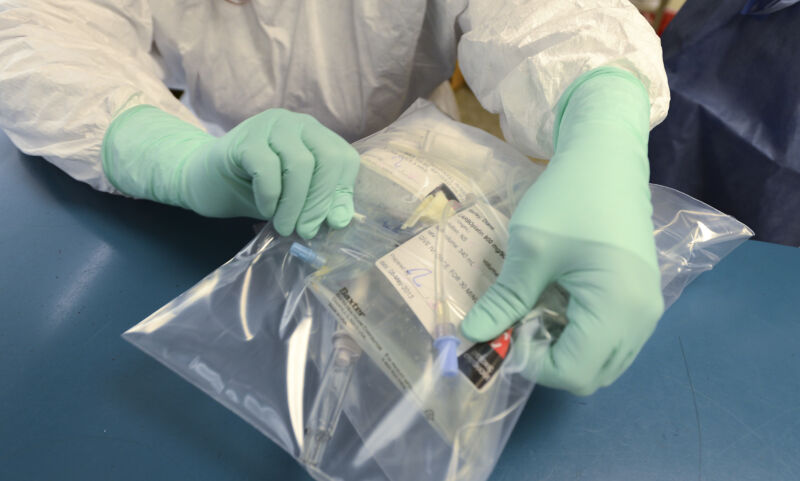 A pharmacy technician holds up a dose of paclitaxel and carboplatin to be verified before being delivered to the patient.