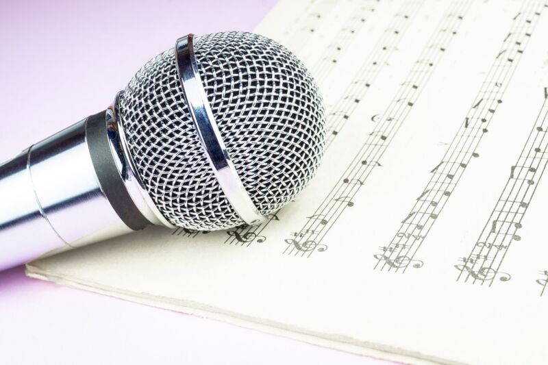 A singer's microphone sitting on a piece of paper displaying musical notes.