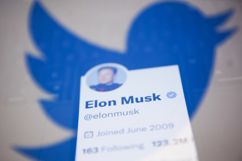 Elon Musk's Twitter account displayed on a phone screen and the Twitter logo displayed on a laptop screen.