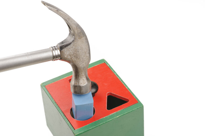A hammer being used to force a square block through a round hole.