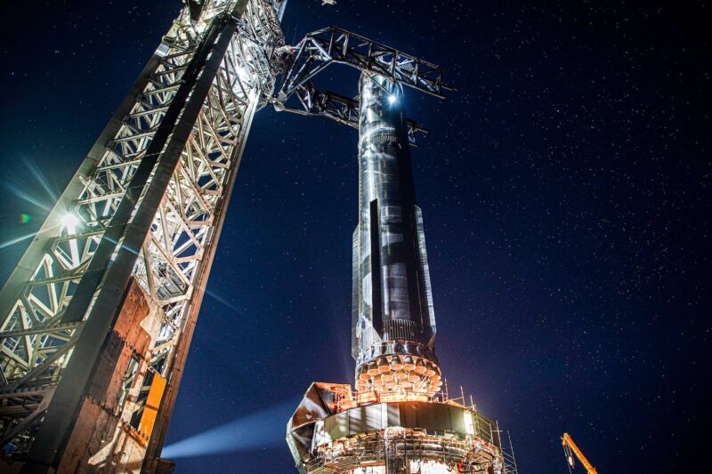 The Super Heavy booster for SpaceX's next Starship test flight is raised onto its launch mount at the Starbase facility in South Texas.