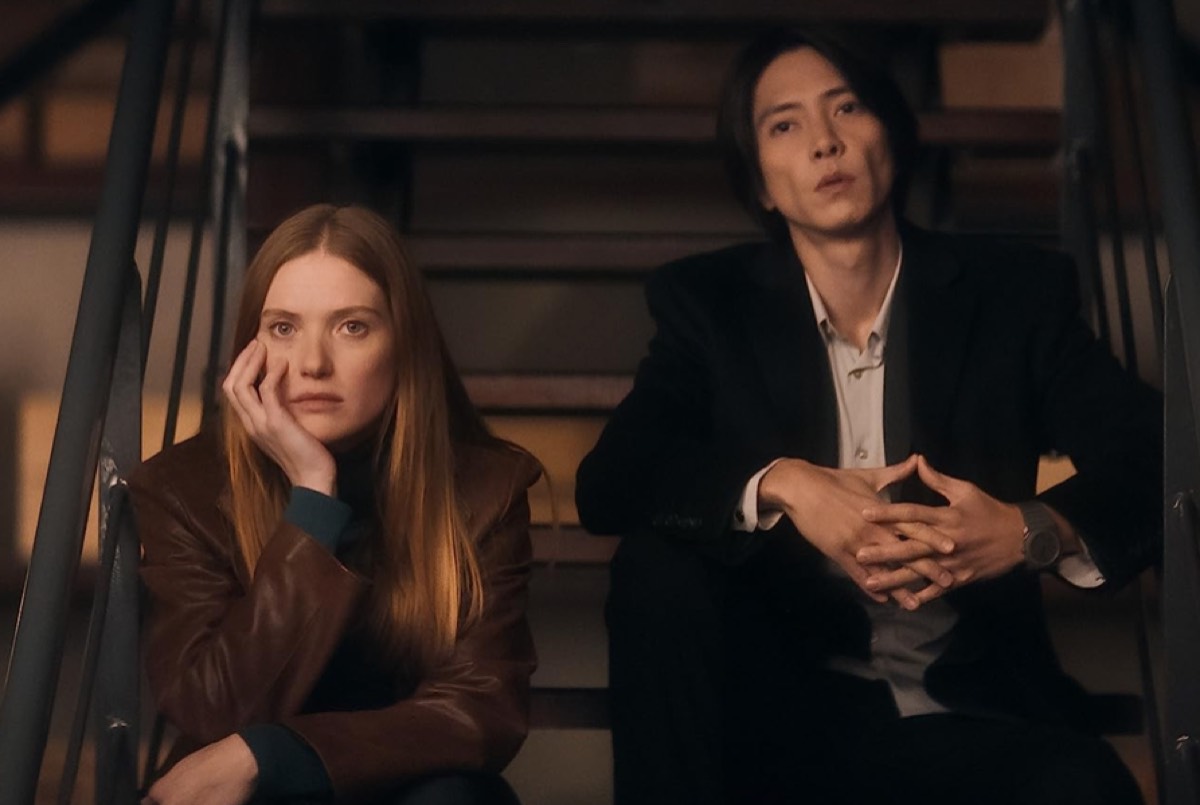 red-haired woman and Japanese man on steps, looking dejected.