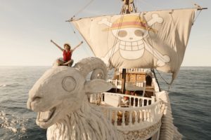 Boy in straw hat on the proof of a pirate ship, arms outstretched to the sky
