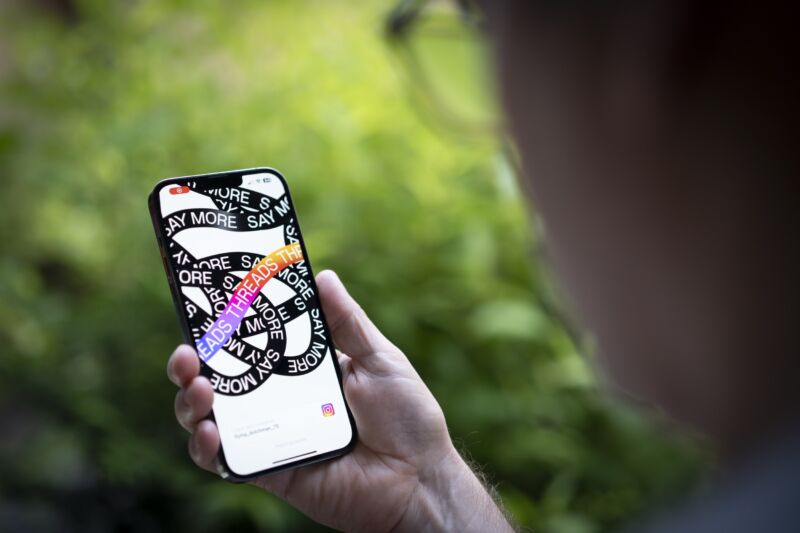 Man holding a smartphone that displays Meta's Threads app.