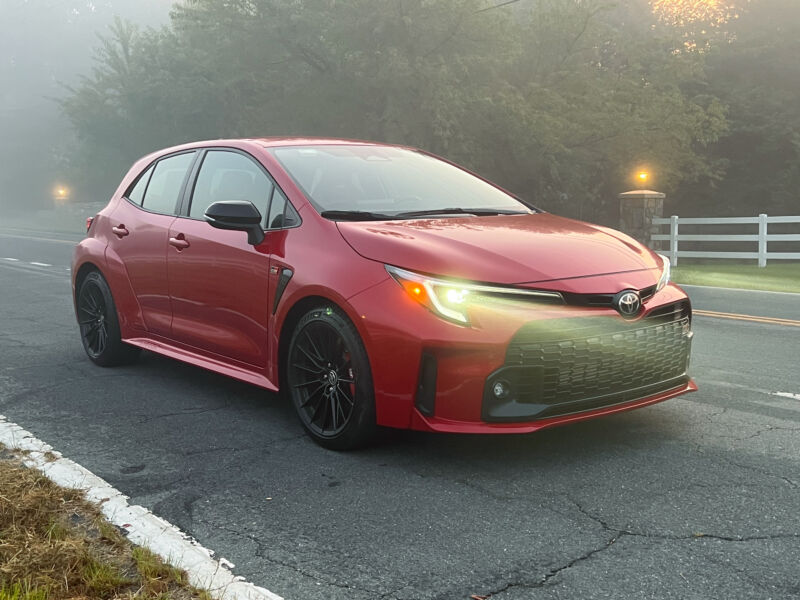 A red Toyota GR Corolla in the early morning fog