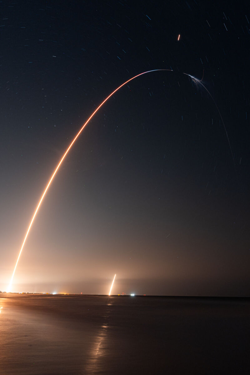 This long exposure photo of the Crew-7 launch shows SpaceX's Falcon 9 rocket streaking into the sky over NASA's Kennedy Space Center in Florida, followed by the return of the Falcon 9 booster to Earth.