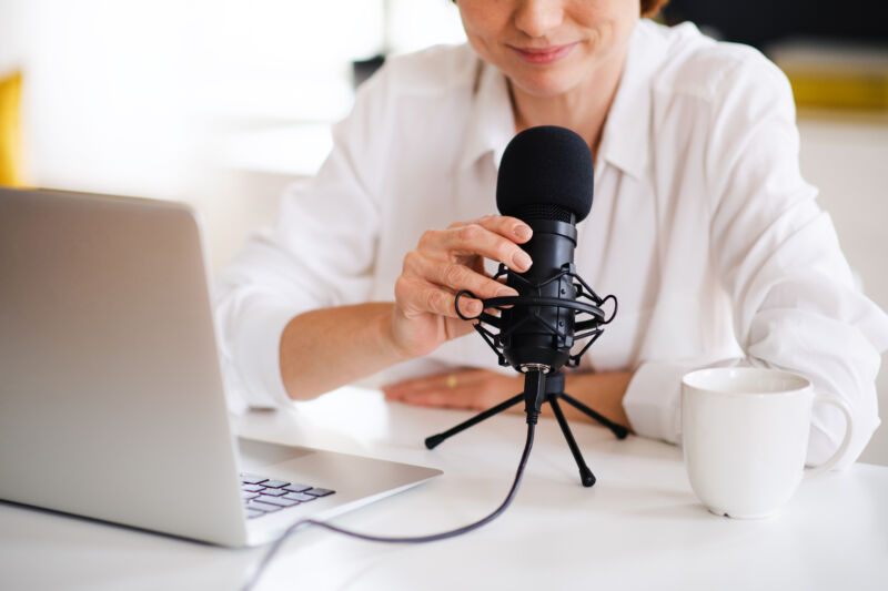 Woman setting up a microphone right by her MacBook