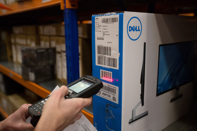 An employee uses a handheld scanner to register the barcode of an outgoing Dell Inc. computer monitor inside the warehouse of an order fulfillment centre,