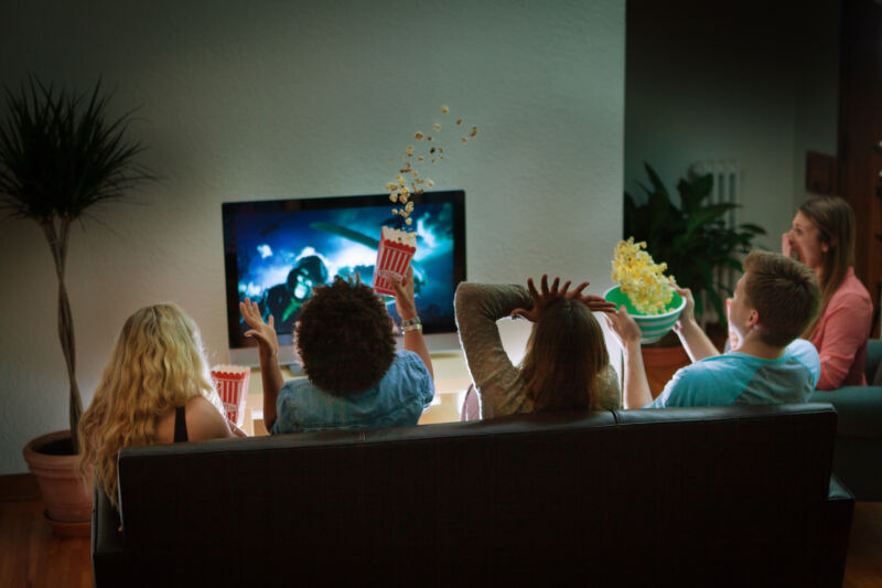 friends watching a scary movie in a living room during scary moment, with popcorn flying