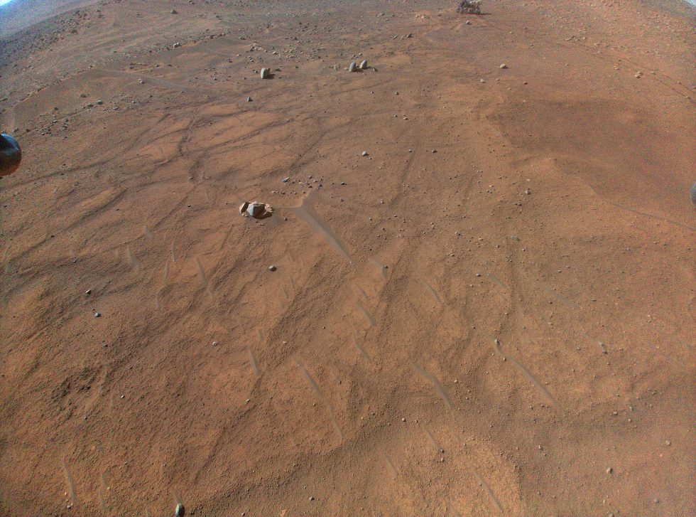 This image of NASA's Mars Perseverance rover, seen at top right of center, was taken by the Mars Innovation helicopter during its 54th flyby on August 3, 2023.