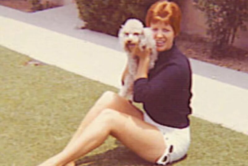 woman with short red hair holding a white dog