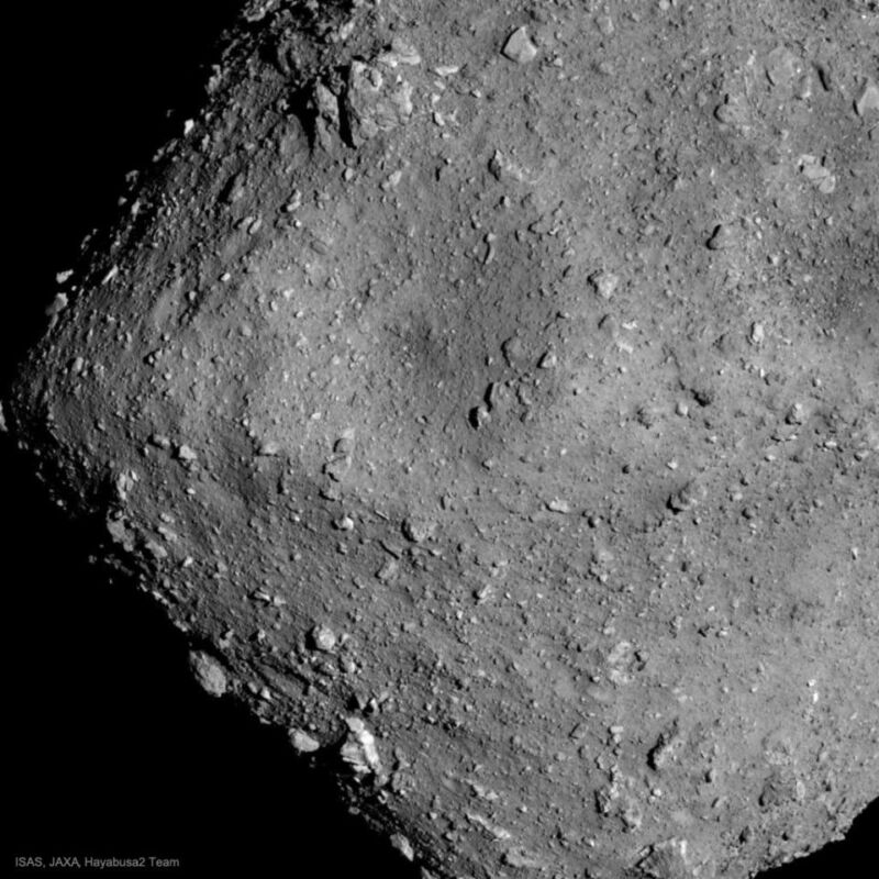 Grey image of a small asteroid's surface, showing many rocks and lots of dust.