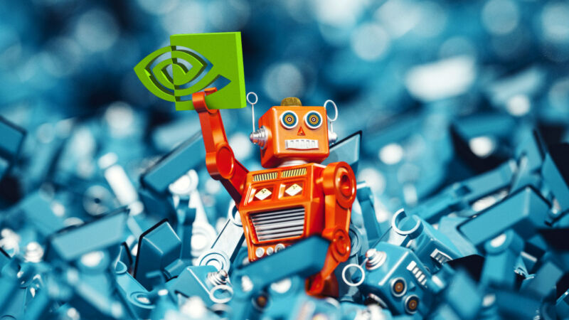 A lone red complete toy robot holding the NVIDIA logo lying on a pile of discarded blue toy robot parts