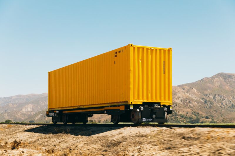 A yellow cargo container rides on an autonomous rail car