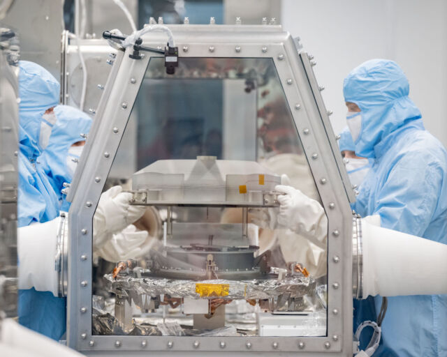 Wetenschappers verwijderen het deksel van de OSIRIS-REx-monsterbak in het Johnson Space Center van NASA in Houston.