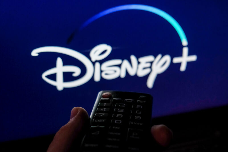 TV remote control is seen with Disney+ logo displayed on a screen