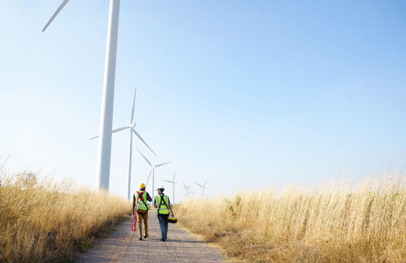 Image of two workers walking among wind turbines.