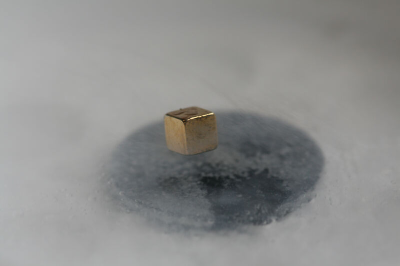 Image of a gold-colored cube floating in a foggy environment above a grey metal plate.