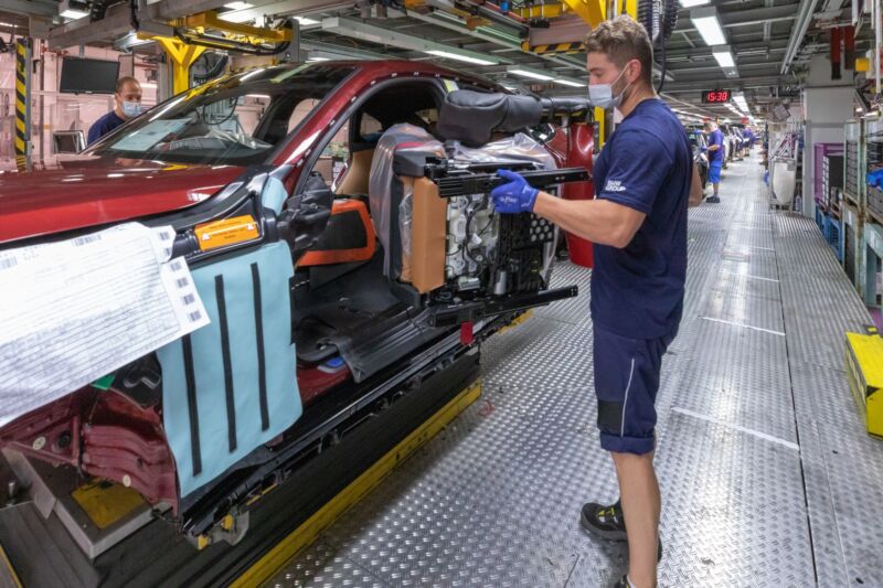 A BMW worker installs a seat in an i4 on the production line