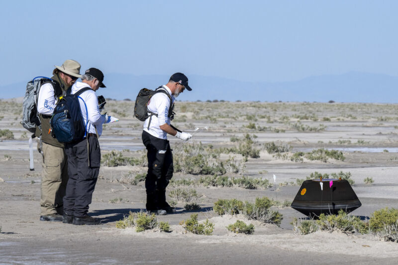 Dante OSIRIS-REx principal investigator Lauretta (right) approaches the sample return capsule at the Utah Test and Training Range on Sunday.