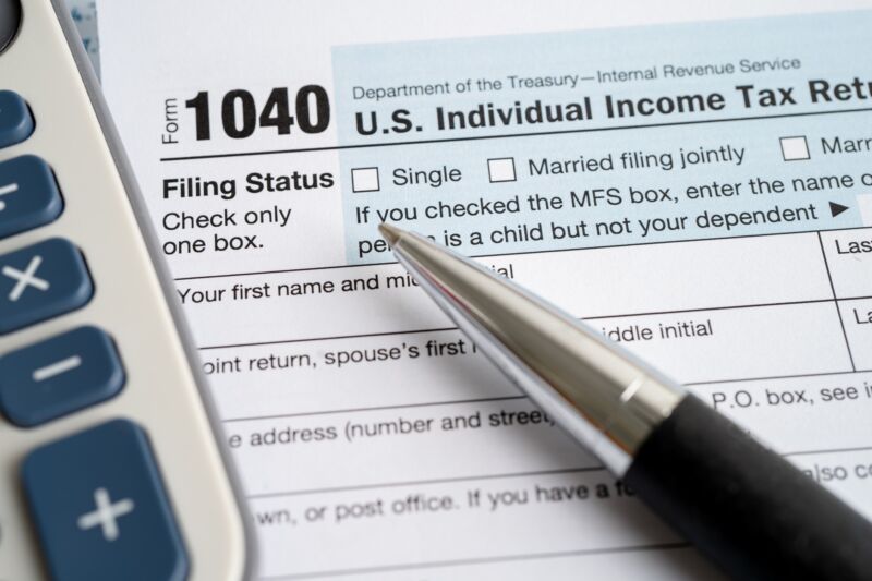 A United States tax filing form. A pen and a calculator sit on top of the form.