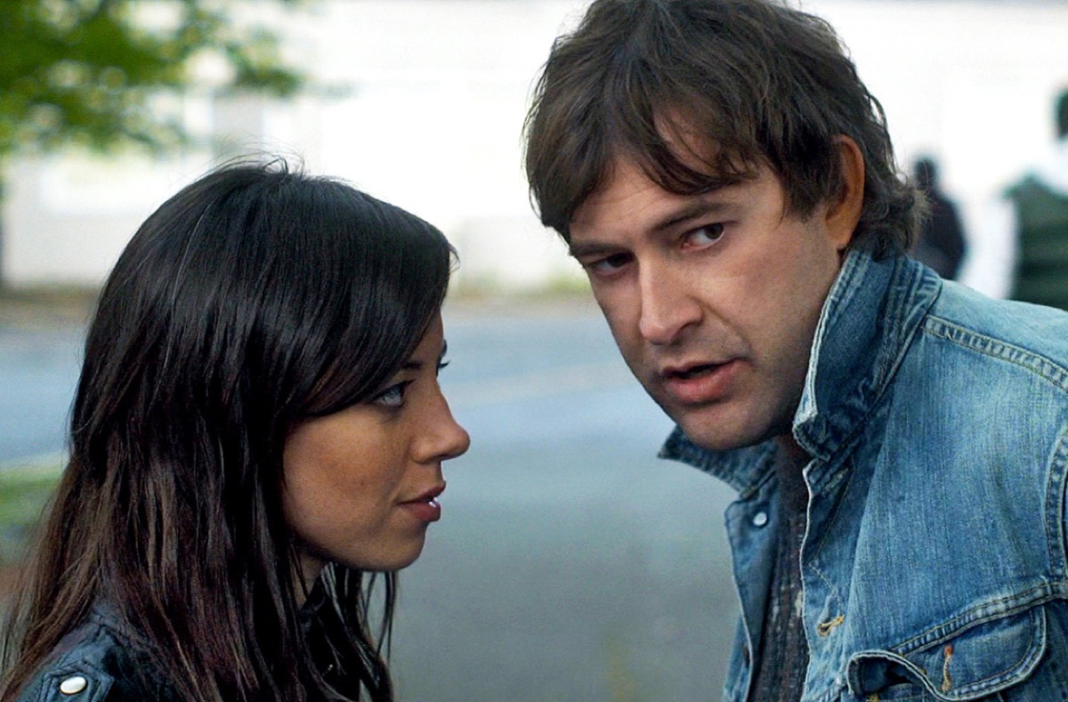 dark haired woman looking at a brown haired man in a denim jacket