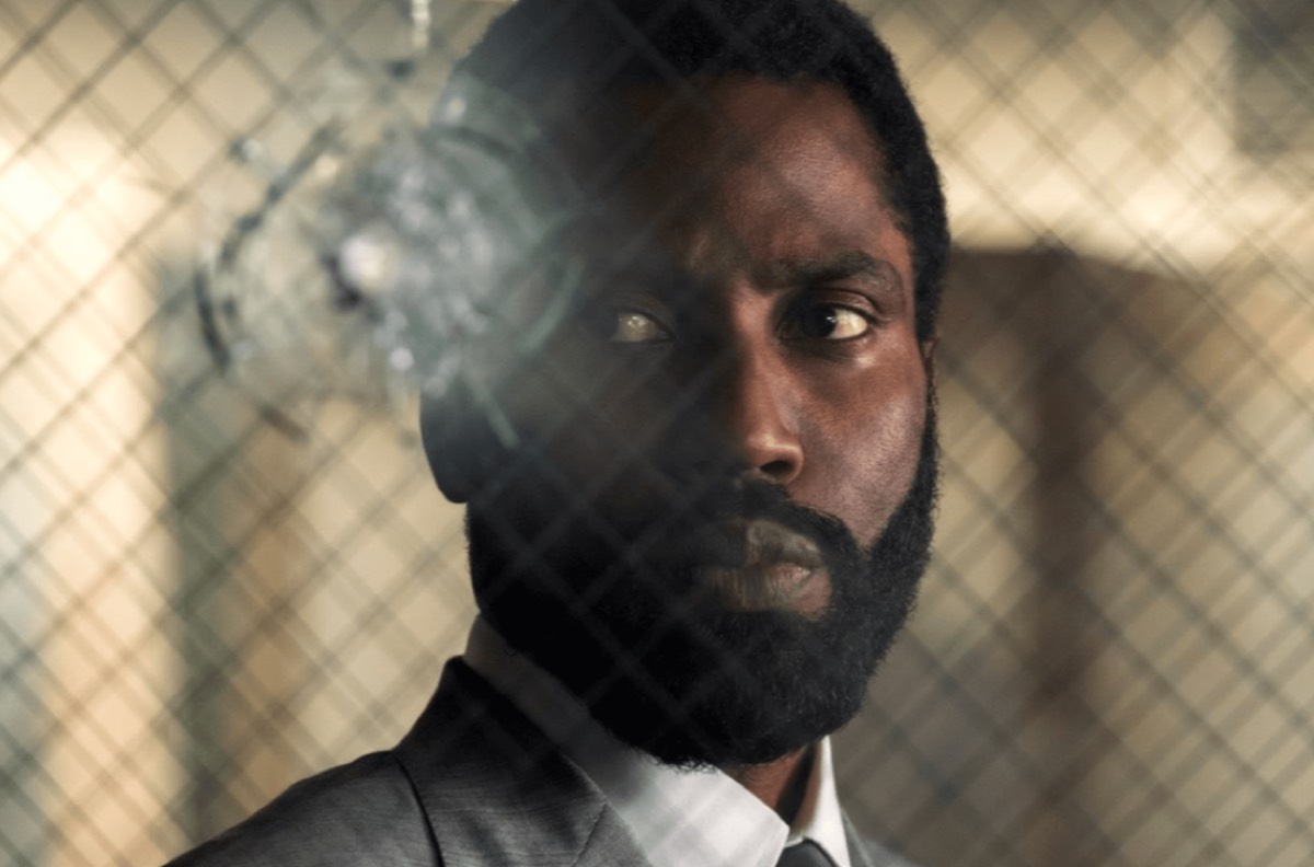 bearded black man looking at a bullet hole in glass