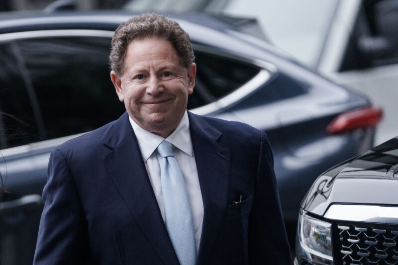 Bobby Kotick, in a suit, approaches a courthouse, looking at the camera.