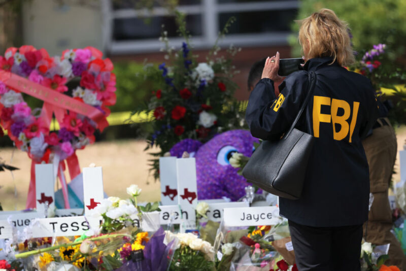 An FBI agent takes a photo of a memorial for victims of a mass shooting at Robb Elementary School on May 27, 2022, in Uvalde, Texas. Police were criticized for delaying for more than an hour confronting the shooter. Such criticism has led some police to respond more aggressively to hoax school shooting calls.