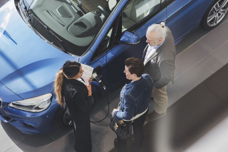 High angle view of saleswoman talking to customers at car showroom