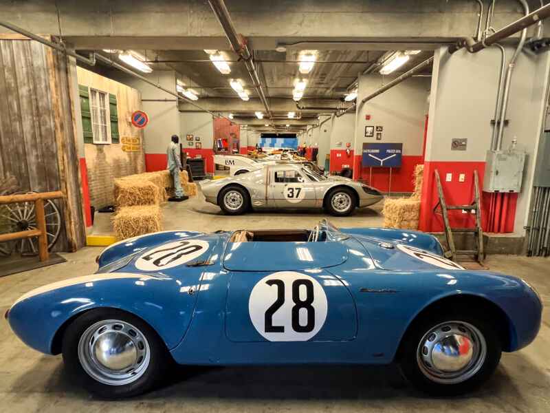A garage full of Porsche race cars. A blue 550 is in the foreground