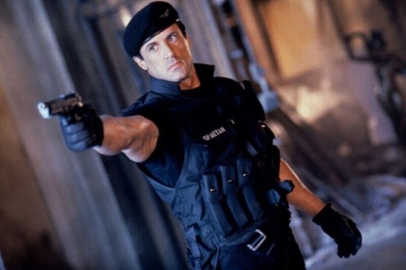 Stallone ion riot gear pointing a pistol