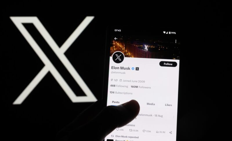 La cuenta de Elon Musk en X (antes Twitter) se muestra en un teléfono inteligente junto a un gran logotipo de X.