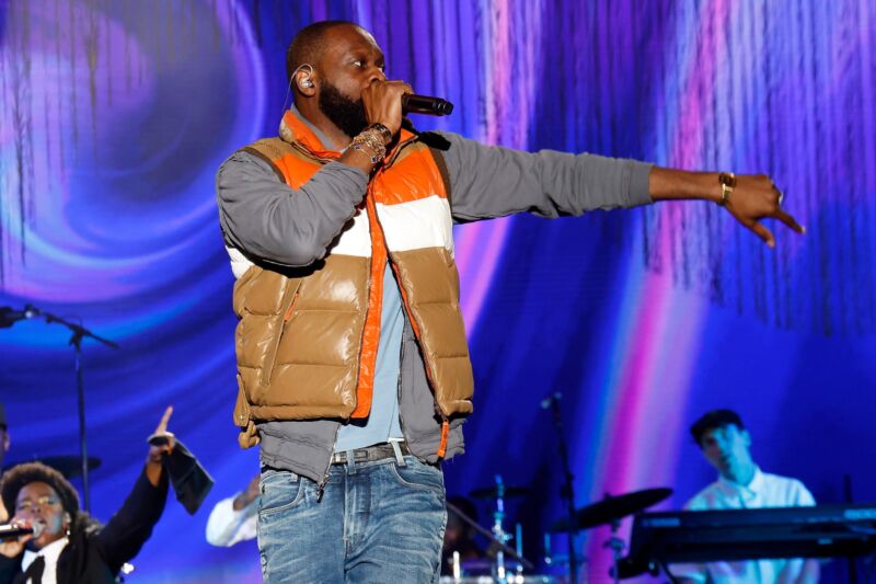 Rapper Pras Michel performing on stage while holding a microphone.