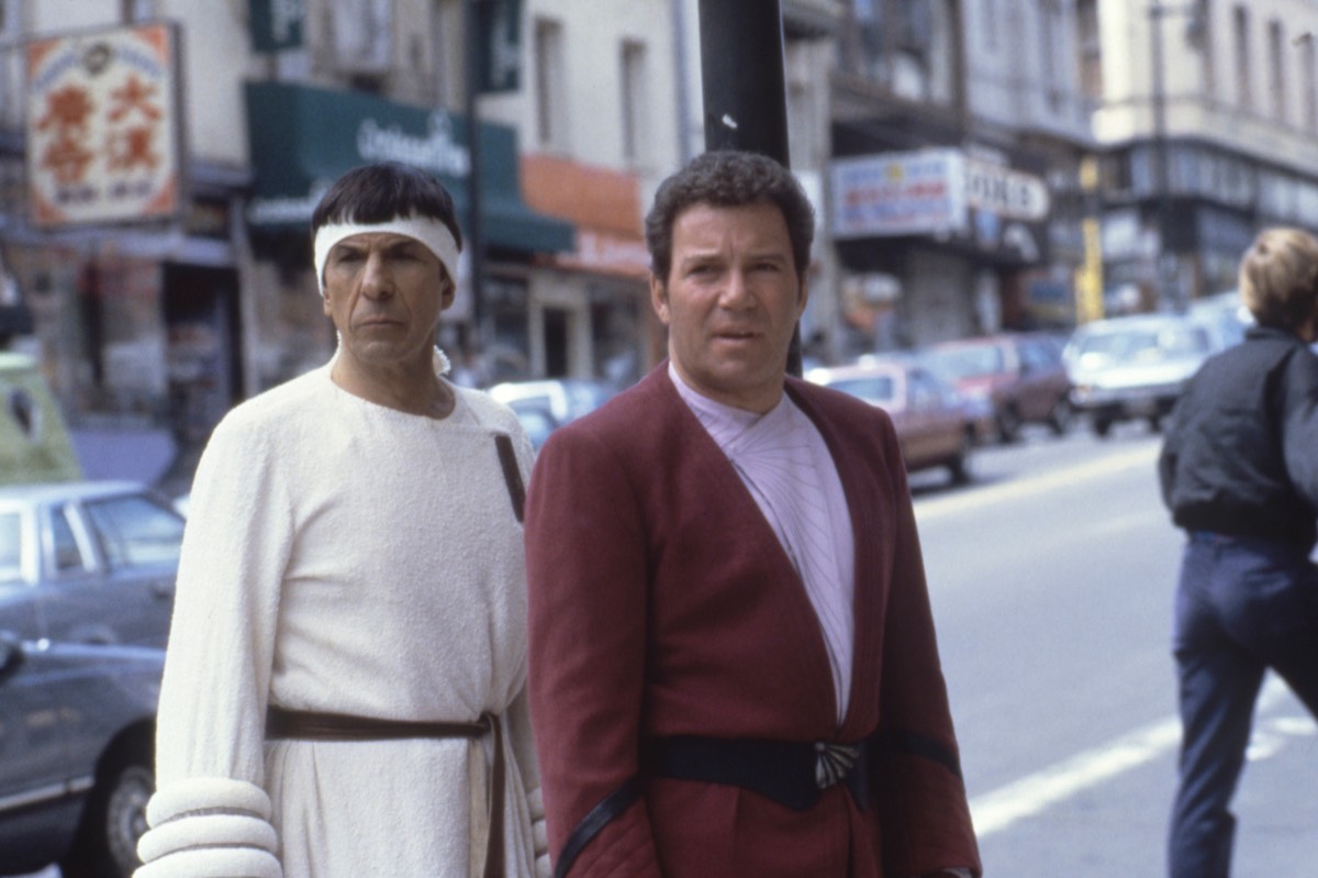 Spock in white robes, Kirk in red robes standing in 1980s San Francisco