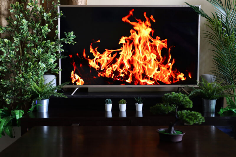 Close-up image of Smart Television screensaver of roaring , dancing flames from beach barbecue burning wood against night sky, domestic life concept