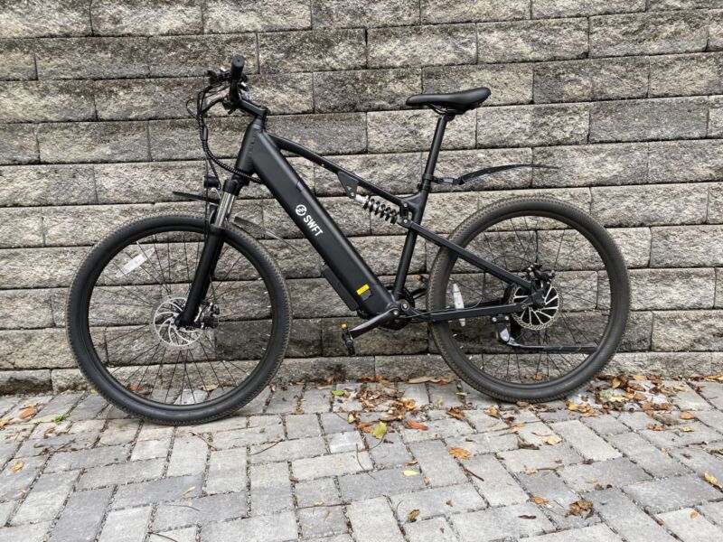 Image of a brown mountain bike leaned up against a grey stone wall.