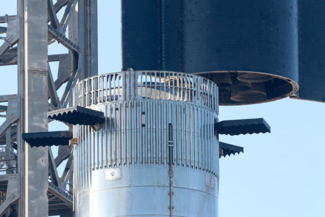 Este primer plano muestra las cuatro aletas de rejilla cerca de la parte superior del propulsor Super Heavy.  Los seis motores Raptor en la parte inferior de la etapa superior de Starship también fueron visibles cuando SpaceX lo levantó del propulsor.