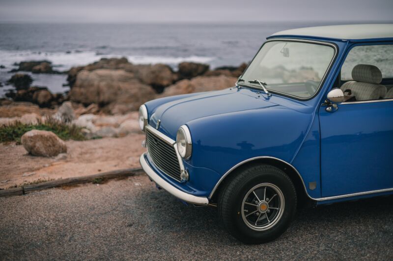 The front half of a classic Mini Cooper, seen by the sea.