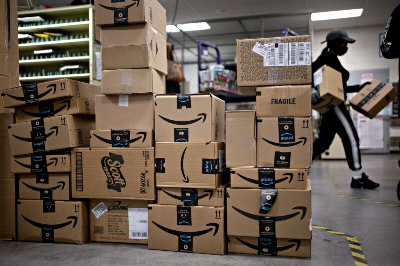A large pile of Amazon boxes inside a postal service building.