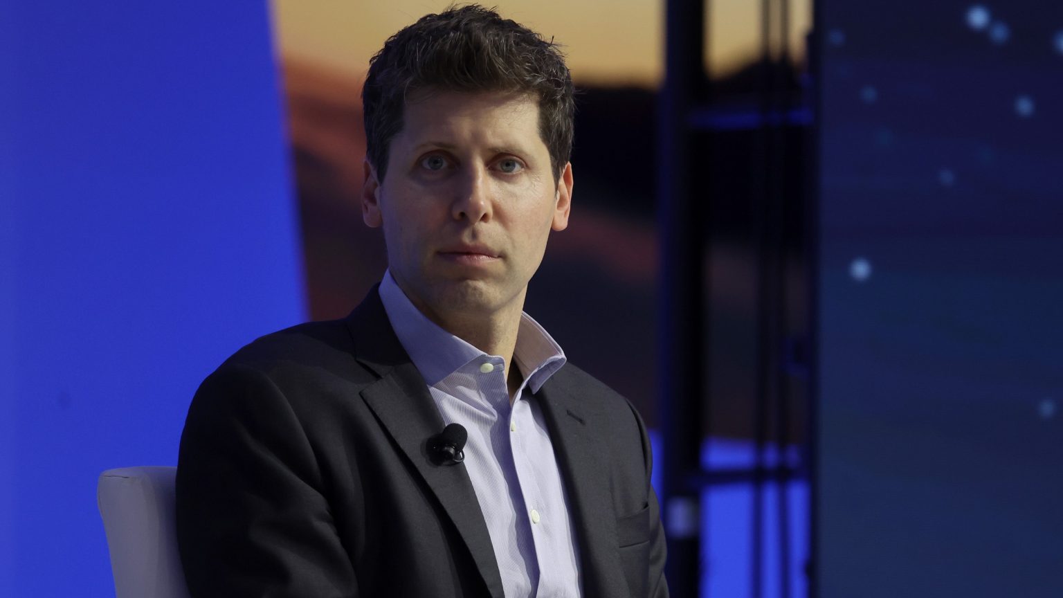 Sam Altman sits on stage at a conference.