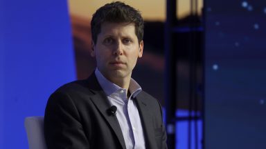 Sam Altman sits on stage at a conference.