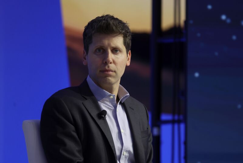 Sam Altman sits on stage at a conference.