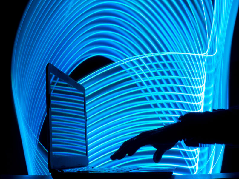 Hand reaching for laptop with blue swirls in the background