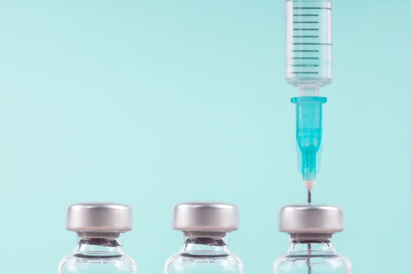 Image of a syringe above three drug vials
